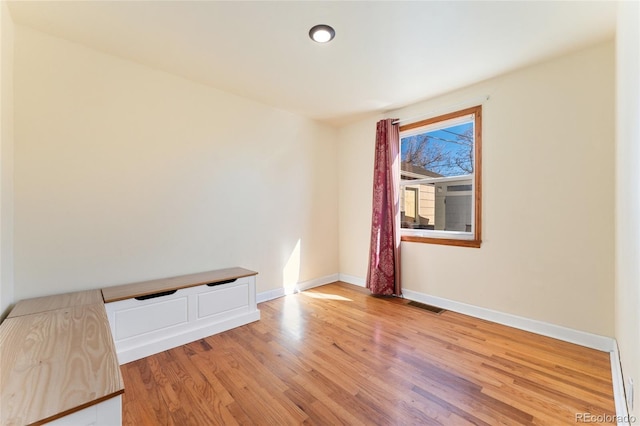 empty room featuring light wood finished floors, visible vents, and baseboards