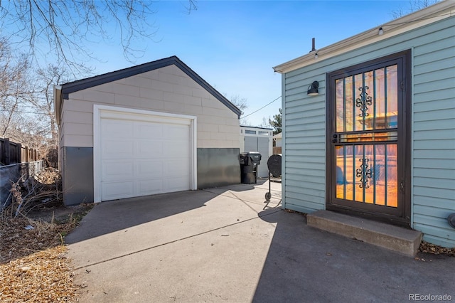 detached garage with concrete driveway and fence