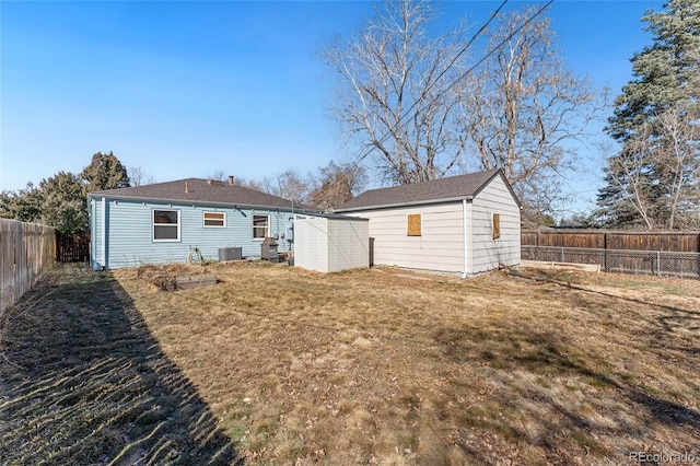 back of house with an outbuilding, a yard, a fenced backyard, and central air condition unit