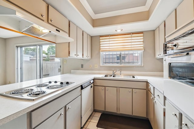 kitchen with sink, a tray ceiling, white appliances, and light tile floors