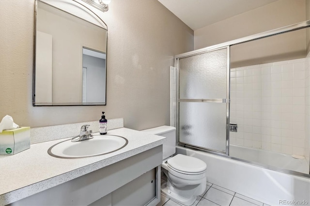 full bathroom featuring combined bath / shower with glass door, oversized vanity, toilet, and tile floors