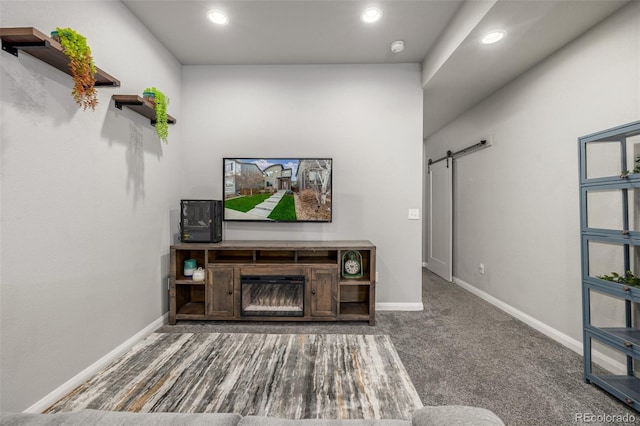 carpeted living room featuring a barn door, recessed lighting, a glass covered fireplace, and baseboards