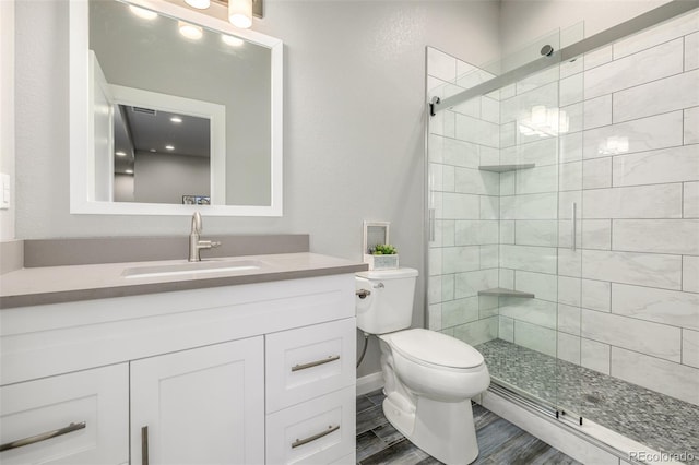 full bathroom featuring wood finished floors, a shower stall, toilet, and vanity