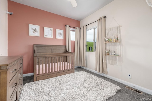 bedroom featuring visible vents, carpet flooring, ceiling fan, a nursery area, and baseboards