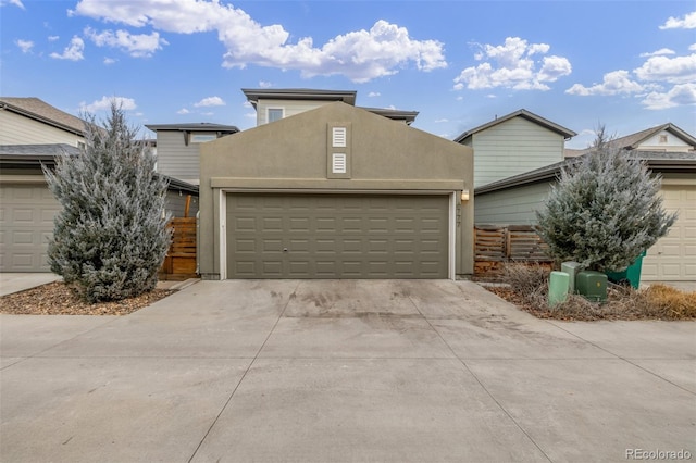 view of front of home with concrete driveway, an attached garage, and stucco siding