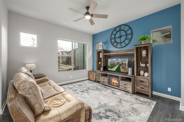 living area featuring wood finished floors, a ceiling fan, and baseboards