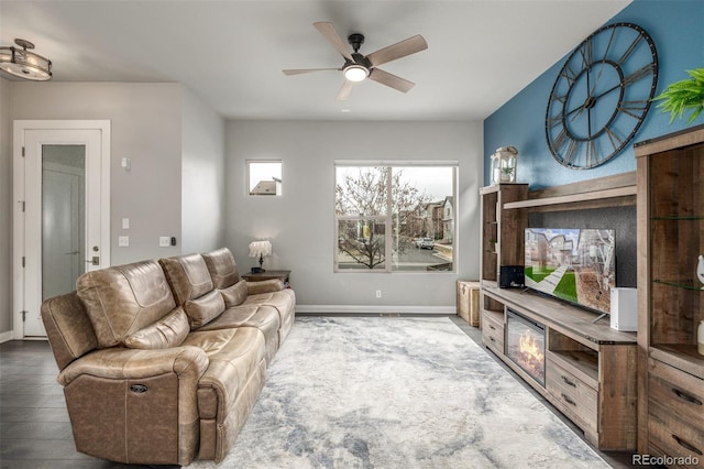 living area featuring a ceiling fan, baseboards, and wood finished floors