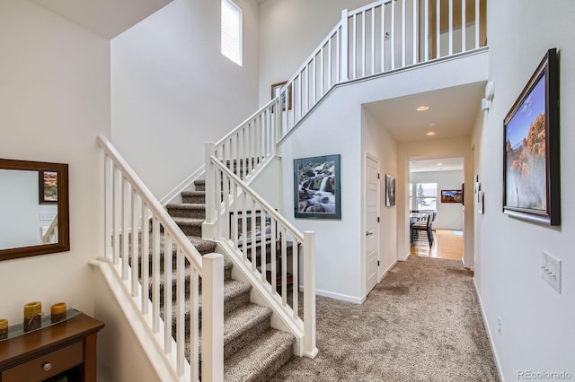 stairs with a towering ceiling, carpet flooring, baseboards, and recessed lighting