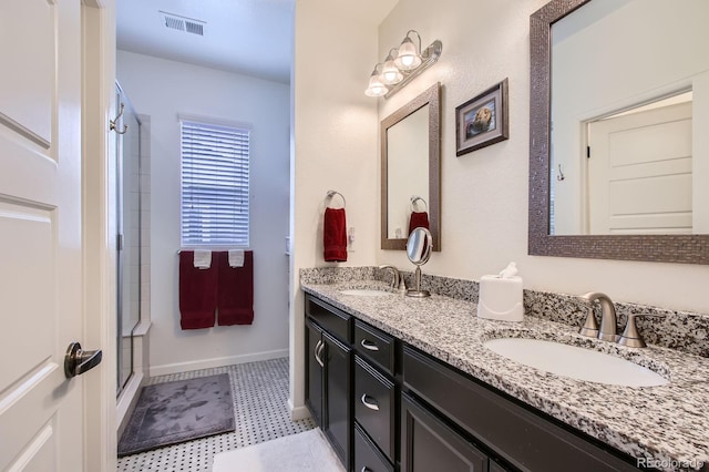full bathroom featuring double vanity, an enclosed shower, baseboards, and a sink