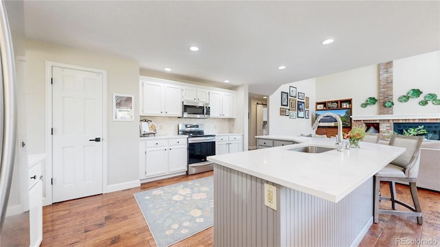 9992 Cottoncreek Dr, Highlands Ranch, CO 80130 - kitchen featuring stainless steel appliances, light wood-style flooring, a large island with sink, open floor plan, and white cabinets