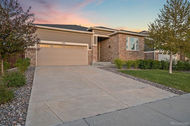 view of front of home featuring stone siding, a garage, driveway, and a lawn