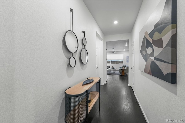 hallway featuring dark wood-style flooring, recessed lighting, and baseboards
