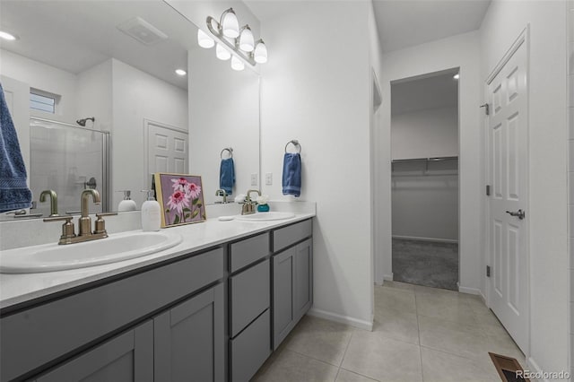 full bath with a shower stall, tile patterned flooring, double vanity, a walk in closet, and baseboards