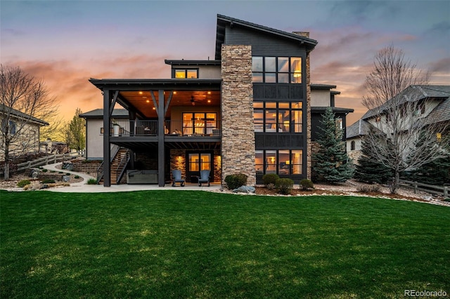 rear view of house featuring stairway, a patio, a yard, and stone siding