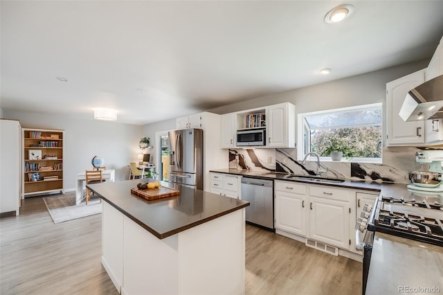 kitchen featuring visible vents, dark countertops, light wood-type flooring, a sink, and stainless steel appliances