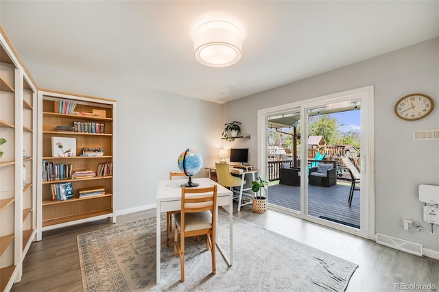 office area with visible vents, baseboards, and wood finished floors