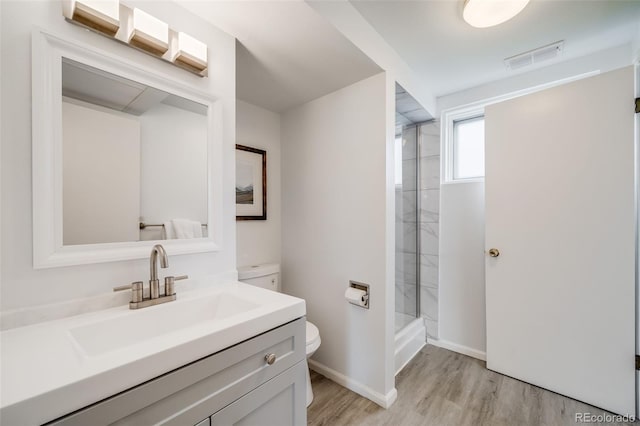 full bathroom featuring visible vents, a shower stall, wood finished floors, vanity, and toilet