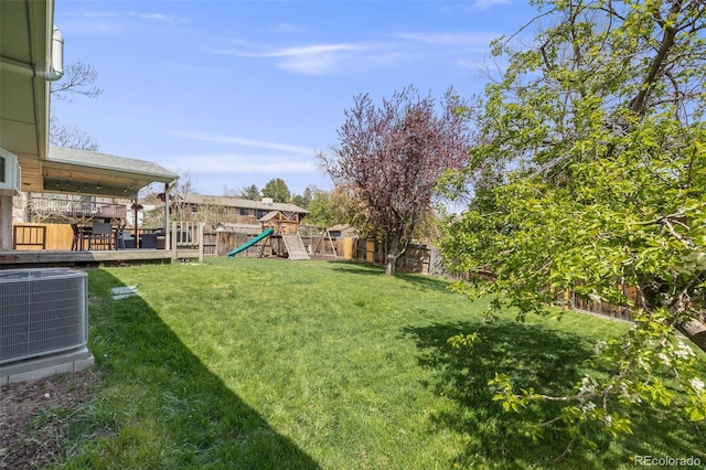 view of yard with central air condition unit, a fenced backyard, and a playground