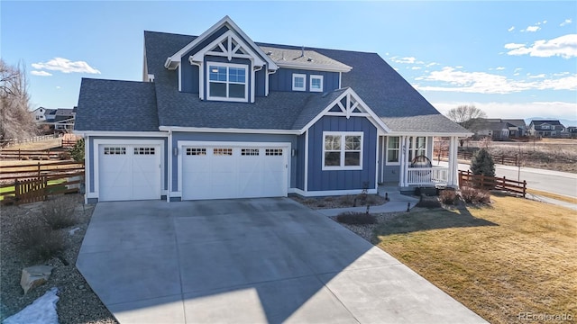 view of front facade with board and batten siding, concrete driveway, roof with shingles, and fence