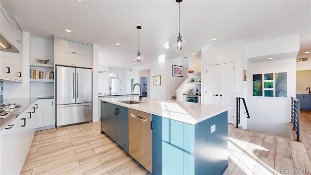 885 Delechant Dr, Erie, CO 80516 - kitchen featuring a kitchen island with sink, stainless steel appliances, light countertops, white cabinetry, and pendant lighting