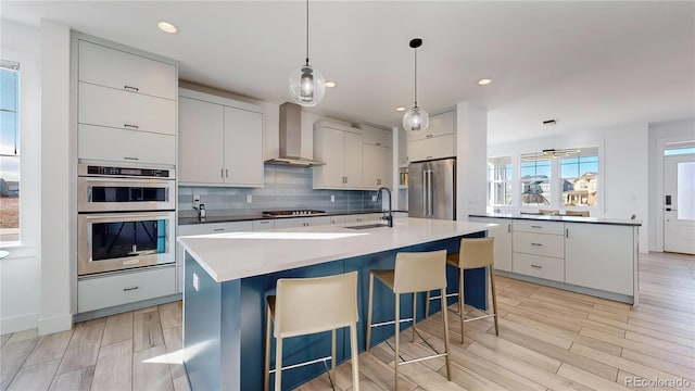 885 Delechant Dr, Erie, CO 80516 - kitchen featuring a sink, appliances with stainless steel finishes, an island with sink, and wall chimney range hood