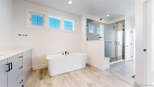 885 Delechant Dr, Erie, CO 80516 - bathroom featuring vanity, a shower stall, wood finished floors, a freestanding tub, and baseboards