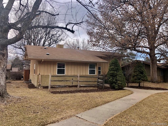 single story home featuring a shingled roof, board and batten siding, a chimney, and fence