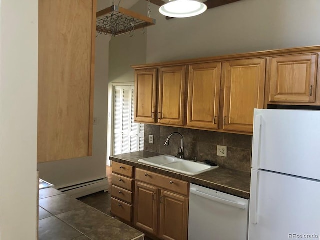 kitchen with white appliances, decorative backsplash, baseboard heating, dark tile patterned floors, and a sink