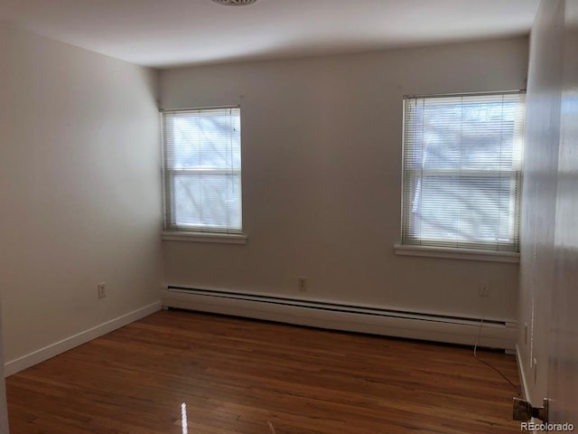 unfurnished room featuring a baseboard radiator, baseboards, and dark wood finished floors