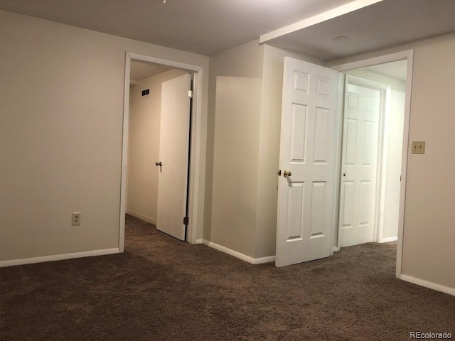 unfurnished room with dark colored carpet, visible vents, and baseboards