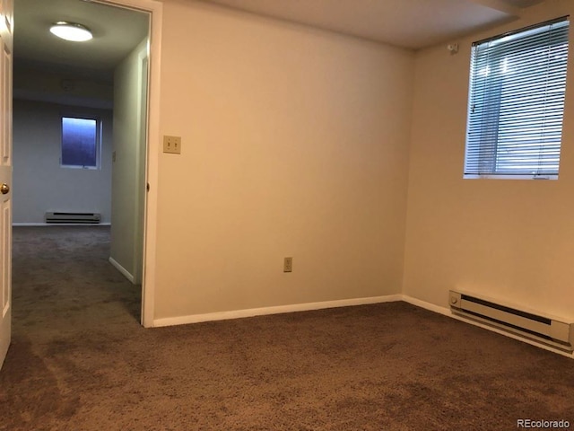 empty room featuring dark colored carpet, a baseboard radiator, and baseboards