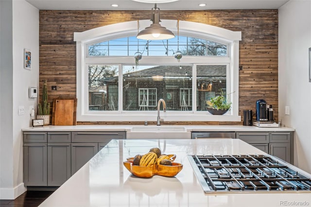 kitchen with gray cabinets, light countertops, a sink, and gas cooktop