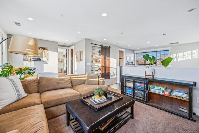 living room with a barn door, visible vents, and recessed lighting