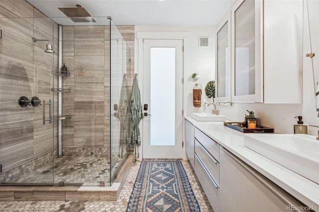 full bathroom with double vanity, a shower stall, visible vents, and a sink