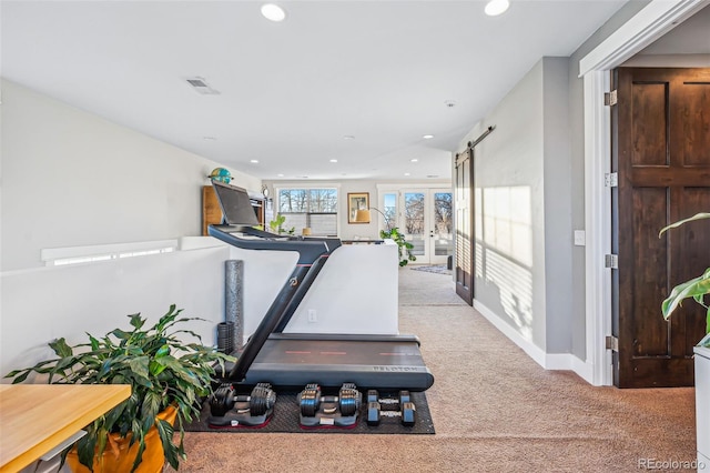 exercise room with light carpet, a barn door, visible vents, and recessed lighting