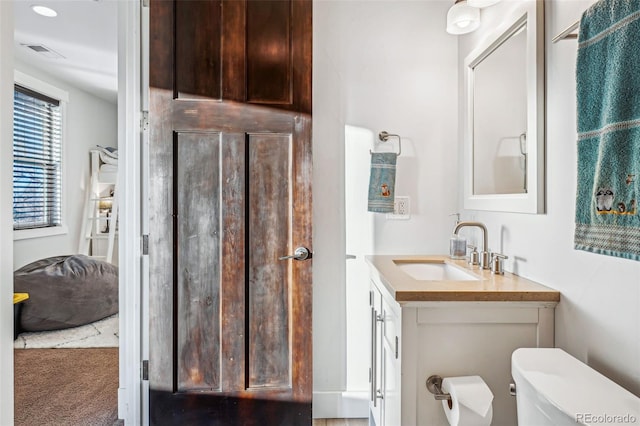 half bathroom with toilet, vanity, and visible vents