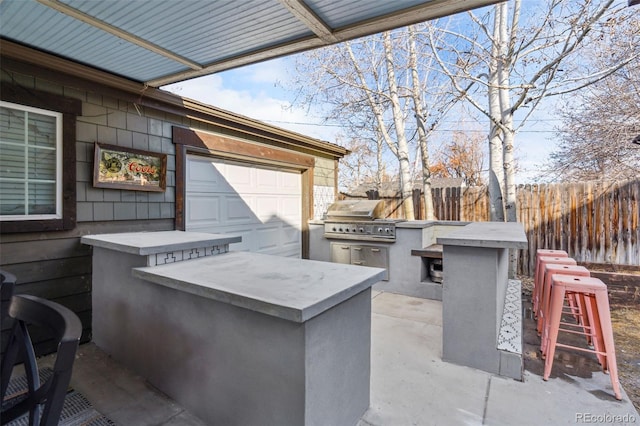 view of patio with fence, exterior kitchen, and area for grilling