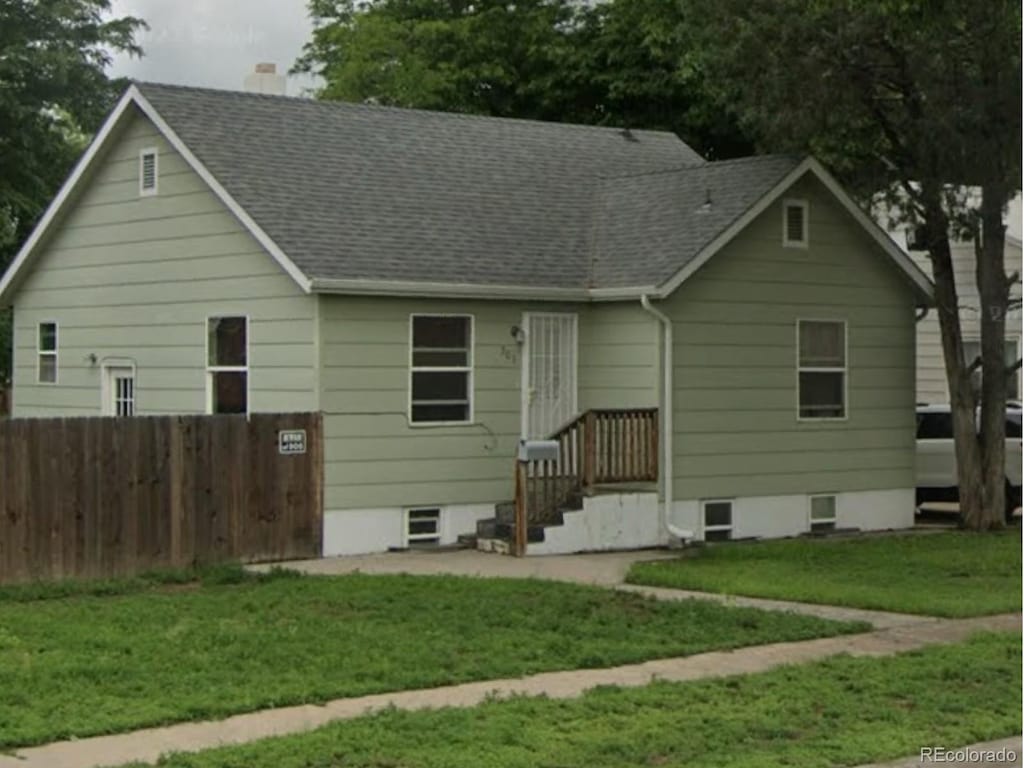 view of front of property with a front lawn, a chimney, a shingled roof, and fence