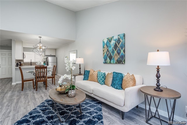 living room with light wood-type flooring and an inviting chandelier