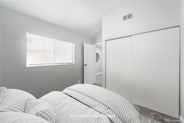 bedroom featuring vaulted ceiling, a closet, and carpet flooring