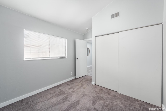 unfurnished bedroom with light carpet, a closet, and lofted ceiling