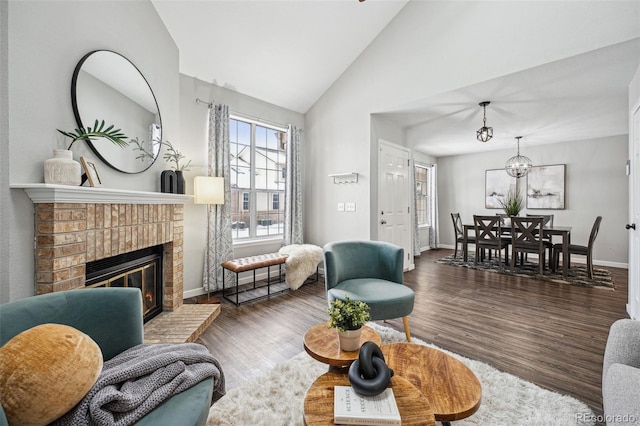 living room with dark hardwood / wood-style flooring, lofted ceiling, a notable chandelier, and a fireplace