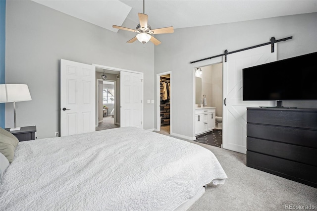 bedroom featuring lofted ceiling, a walk in closet, a closet, ceiling fan, and a barn door