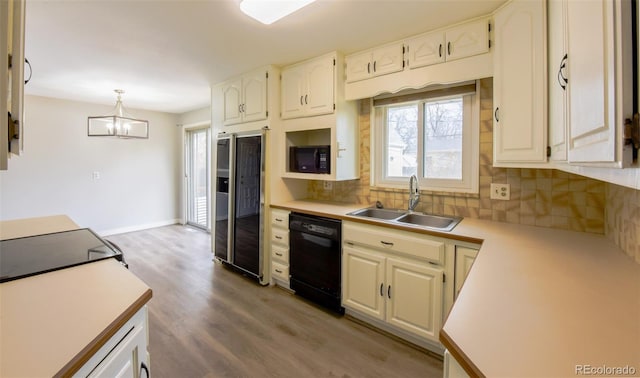 kitchen with sink, black appliances, decorative light fixtures, light hardwood / wood-style flooring, and an inviting chandelier