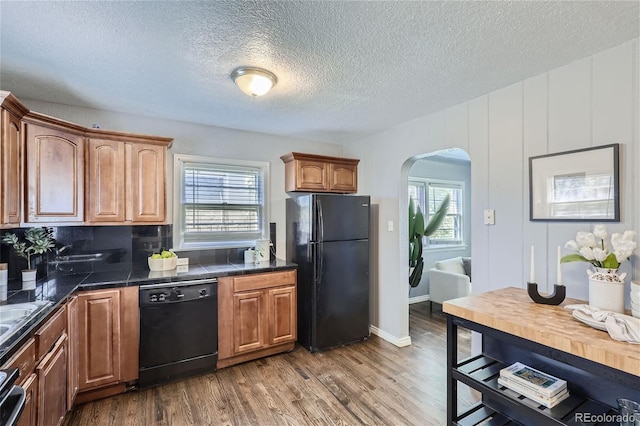 kitchen with a wealth of natural light, arched walkways, dark wood finished floors, and black appliances