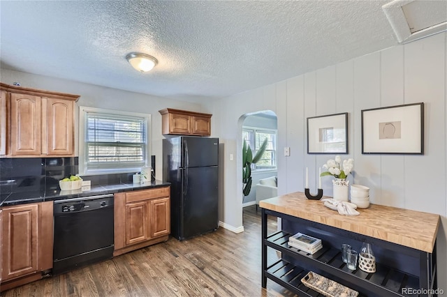 kitchen featuring dark wood-style floors, arched walkways, plenty of natural light, and black appliances