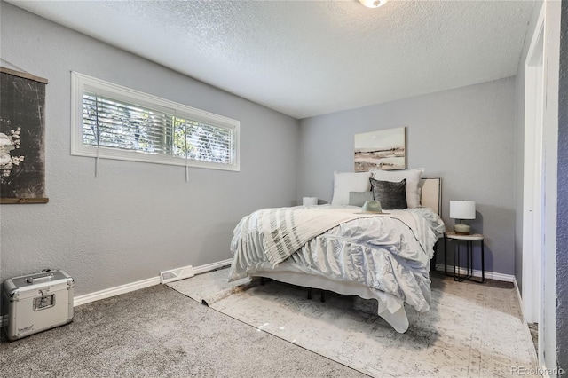 carpeted bedroom featuring visible vents, a textured wall, a textured ceiling, and baseboards