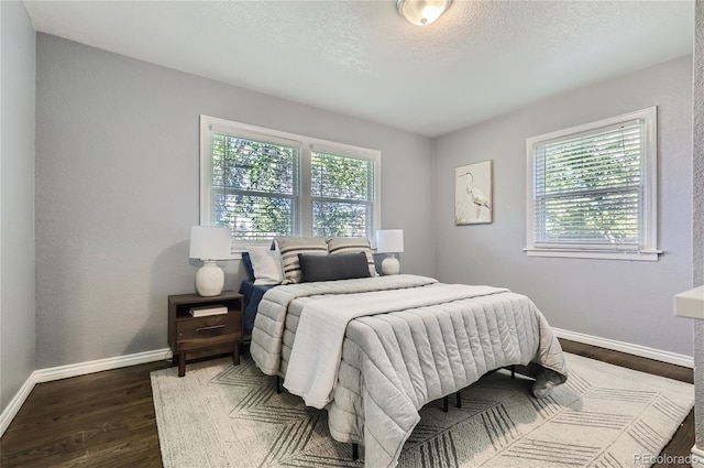 bedroom featuring dark wood-style flooring, multiple windows, a textured ceiling, and baseboards