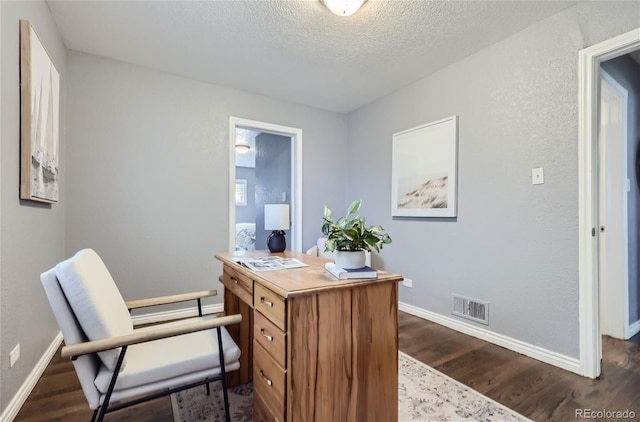 office with baseboards, visible vents, dark wood finished floors, and a textured ceiling