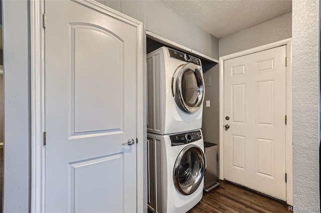 laundry room with a textured ceiling, laundry area, stacked washer / dryer, and dark wood-style flooring